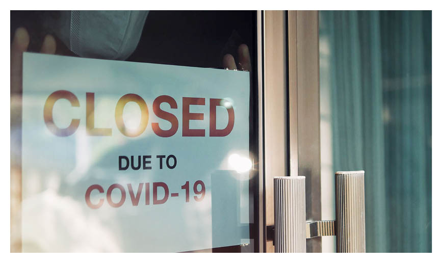 Business office or store shop is closed, bankrupt business due to the effect of novel Coronavirus (COVID-19) pandemic  Unidentified person wearing mask hanging closed sign in background on front door 