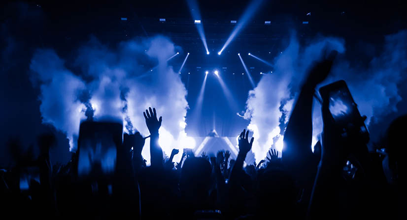 Happy people dance in nightclub party concert and listen to the music from DJ on the stage in the background 