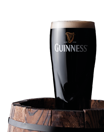 LONDON, UK - APRIL 27, 2018: Original glass of Guinness draught stout beer on top of old wooden barrel  Guinness beer has been produced since 1759 in Dublin, Ireland 