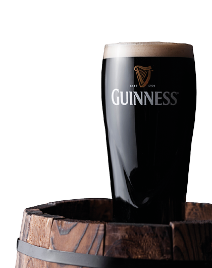 LONDON, UK - APRIL 27, 2018: Original glass of Guinness draught stout beer on top of old wooden barrel  Guinness beer has been produced since 1759 in Dublin, Ireland 