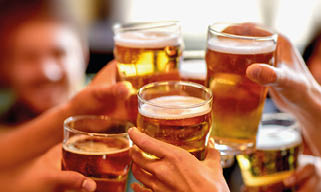 leisure, drinks, celebration, people and holidays concept - smiling friends drinking beer and stitching glasses in a restaurant or pub