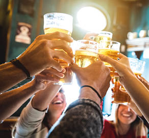 Group of happy friends drinking and toasting beer at brewery bar restaurant - Friendship concept with young people having fun together at cool vintage pub - Focus on middle pint glass - High iso image
