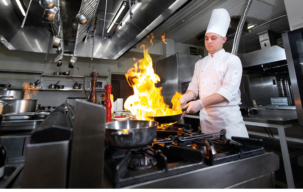Chef cooking with flame in a frying pan on a kitchen stove
