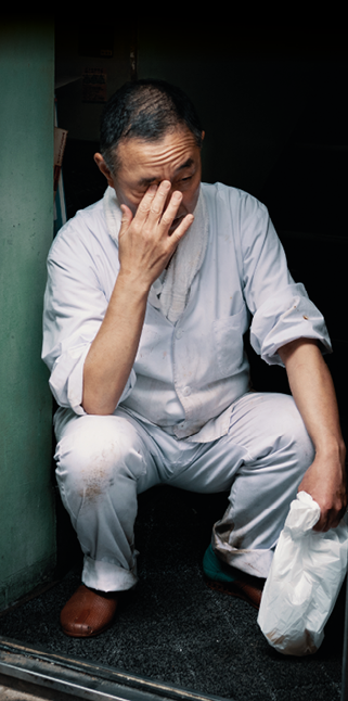 Tokyo, Japan - October 25th, 2018  An exhausted man in a chef's uniform takes a short break away from his work 