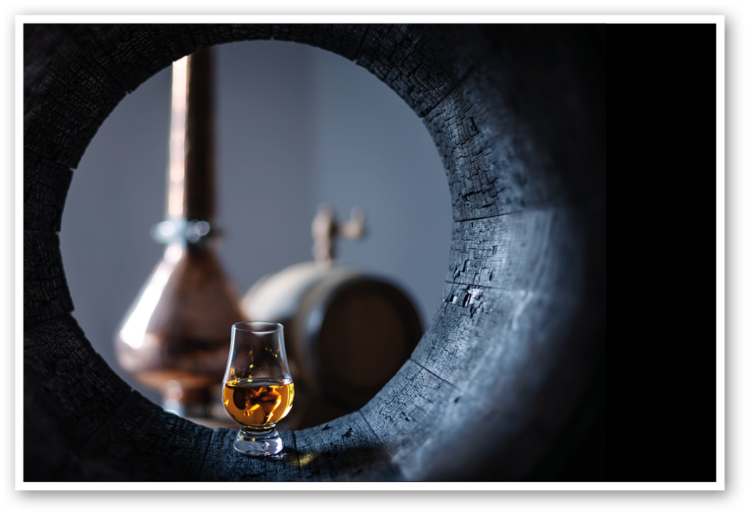 A glass of whiskey in old oak barrel  Copper alambic on background  Traditional alcohol distillery concept