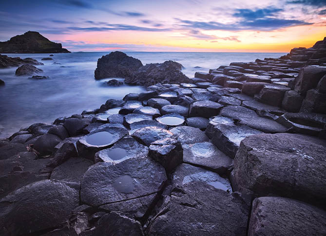 sunset over basalt rocks formation Giant's Causeway, Port Ganny Bay and Great Stookan, County Antrim, Northern Ireland, UK