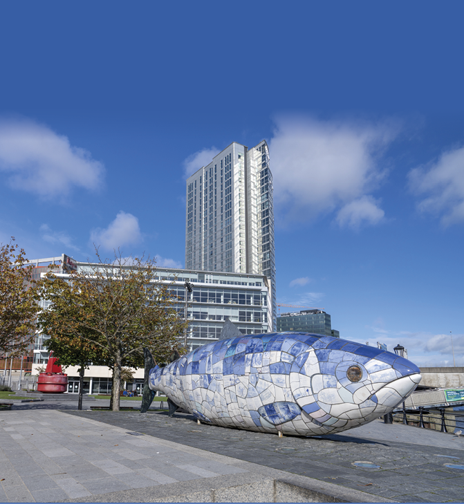 BELFAST, UNITED KINGDOM - Oct 01, 2021: The Big Fish sculpture in street surrounded by buildings on a sunny day in Belfast, United Kingdom