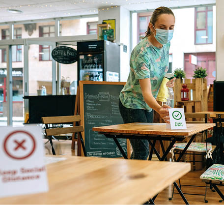 Waitress placing Clean and Safe sign on coffee shop table