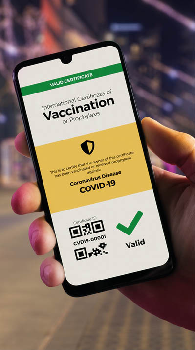 Smartphone displaying a valid digital vaccination certificate for COVID-19 in male's hand, downtown and city bus in background  Vaccination, disease immunity passport, health and surveillance concepts