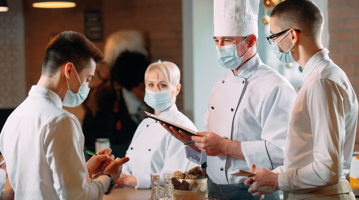 Cafe staff on morning briefing wearing protective masks