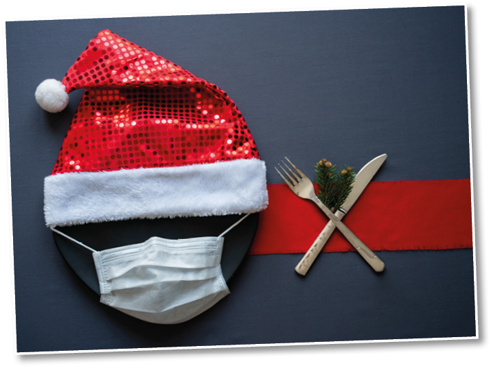 Christmas concept table  Christmas dinner with medical mask  Coronavirus and Christmas 2020 table concept  Face protective mask, santa hat and xmas festive table setting, fork, knife and tree branches