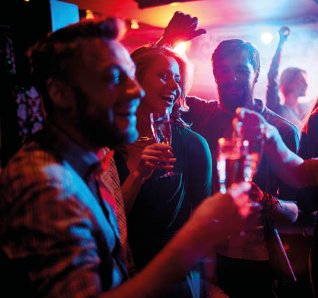 Group of young people celebrating with drinks in nightclub