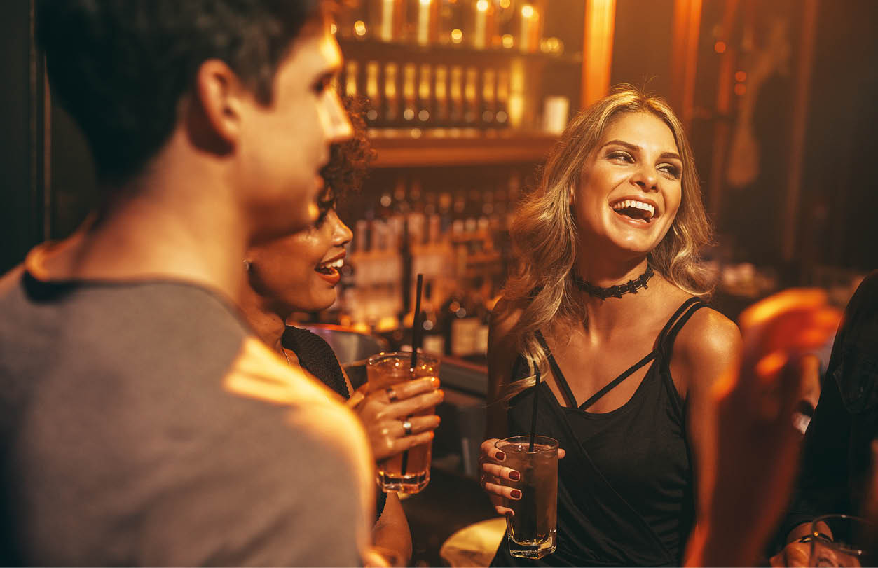 Beautiful young woman having drink at nightclub with friends  Group of people enjoying party in pub 