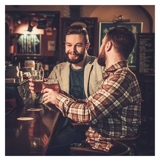 Cheerful old friends drinking draft beer at bar counter in pub 