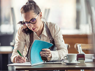 Restaurant owner does bills and paperwork after hours over coffee.
