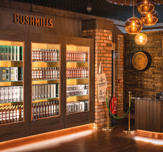 Bushmills, Northern Ireland, Aug 2019 Bushmills whiskey on illuminated shelfs on a display and cash register in distillery visitor centre and shop