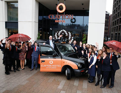 A group of people standing around a car with umbrellas  Description automatically generated with low confidence