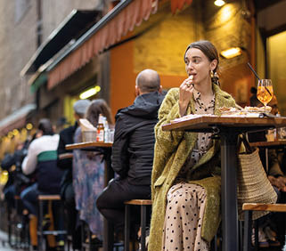 Woman sitting on crowded street at bar or restaurant outdoors in Bologna city  Concept of Italian lifestyle and gastronomy