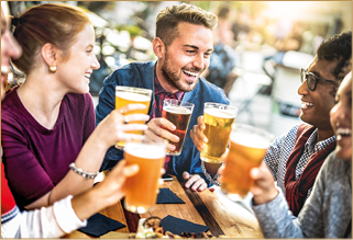 Young people drinking beer pints at brewery bar garden - Genuine beverage life style concept with guys and girls sharing happy hour together at open air pub dehor - Warm sunset backlight filter