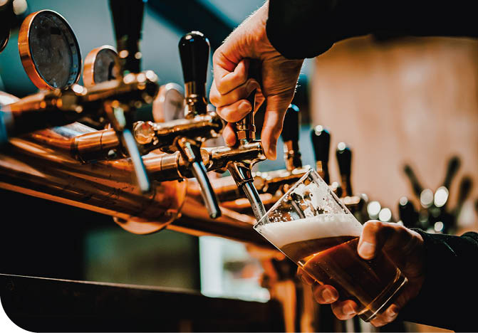 bartender hand at beer tap pouring a draught beer in glass serving in a bar or pub. tap room