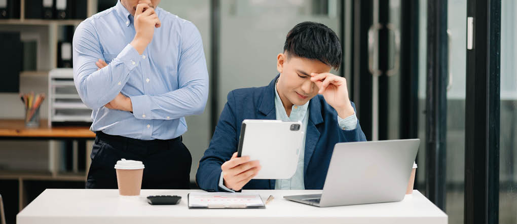 Furious two Asian businesspeople arguing strongly after making a mistake at work in modern office