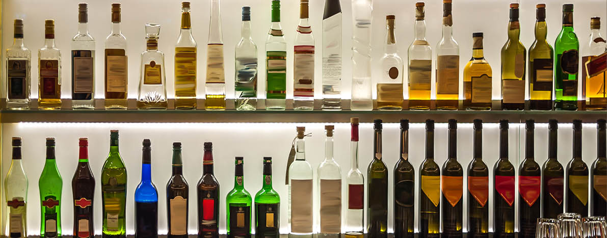 Backlit bottles and glassware behind a bar also known as the back bar  