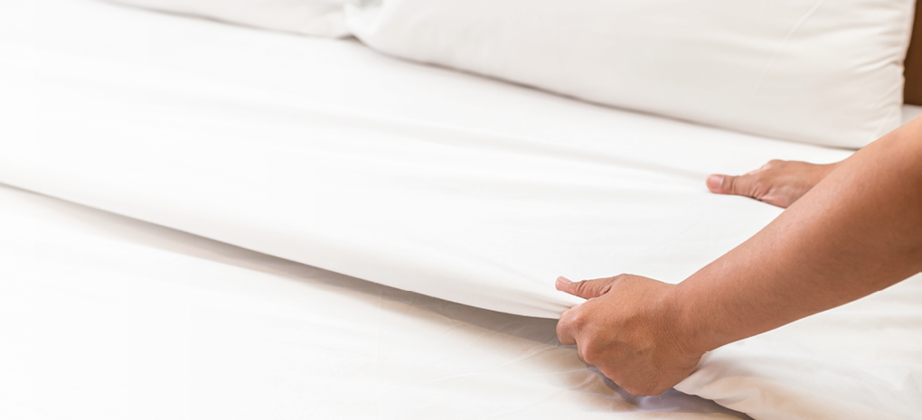 Close up hand set up white bed sheet in hotel room