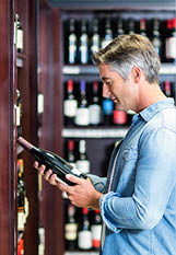 Smiling man holding bottle of wine in supermarket