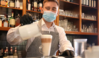 Barista preparing coffee at counter in restaurant. Catering during coronavirus quarantine