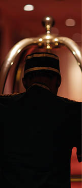 Rear view of servant moving along hotel aisle with baggage cart