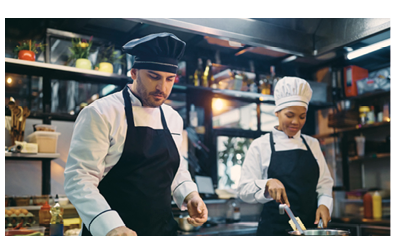 Male chef and his African American female coworker preparing food in a restaurant. 