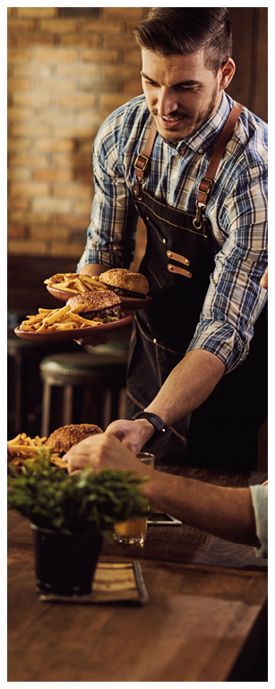 Group of happy friends having fun while waiter is serving them food in a pub.