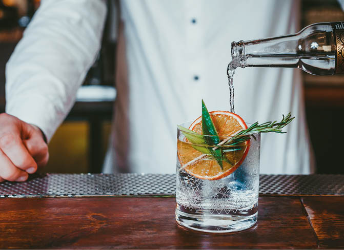 Alcoholic cocktail in bar, Bartender making gin cocktail with garnishes 