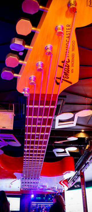 A guitar hanging from the ceiling in a bar. Description generated by AI