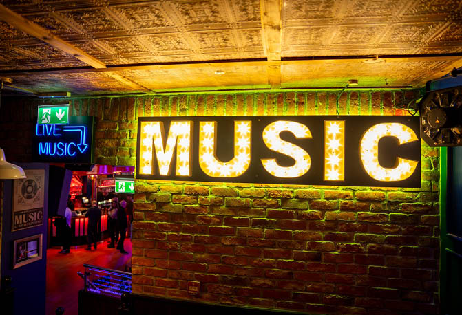 A neon sign that says music. Description generated by AI