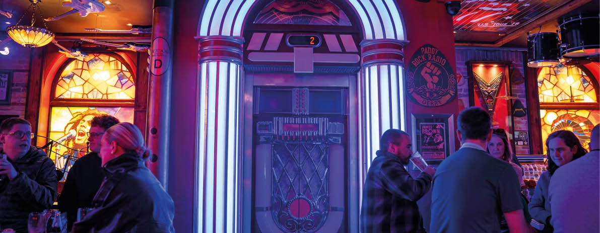 A group of people are sitting at a bar with a neon sign above them. Description generated by AI