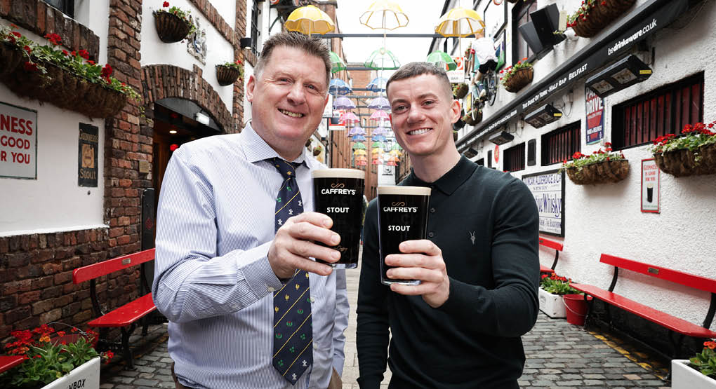 Two men holding glasses of beer. Description generated by AI