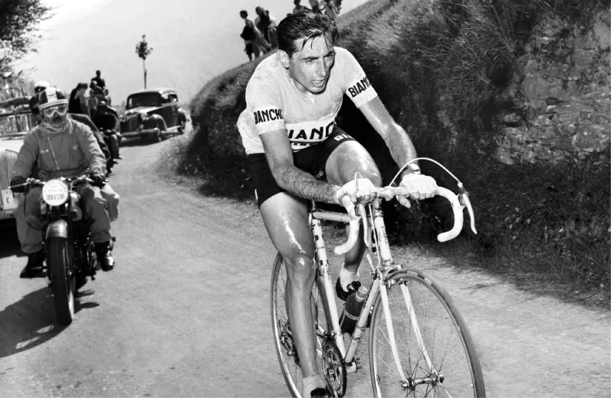 A man riding a bicycle on a road. Description generated by AI