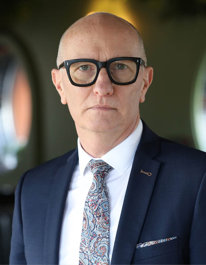 A man wearing a suit and tie with a patterned tie. Description generated by AI