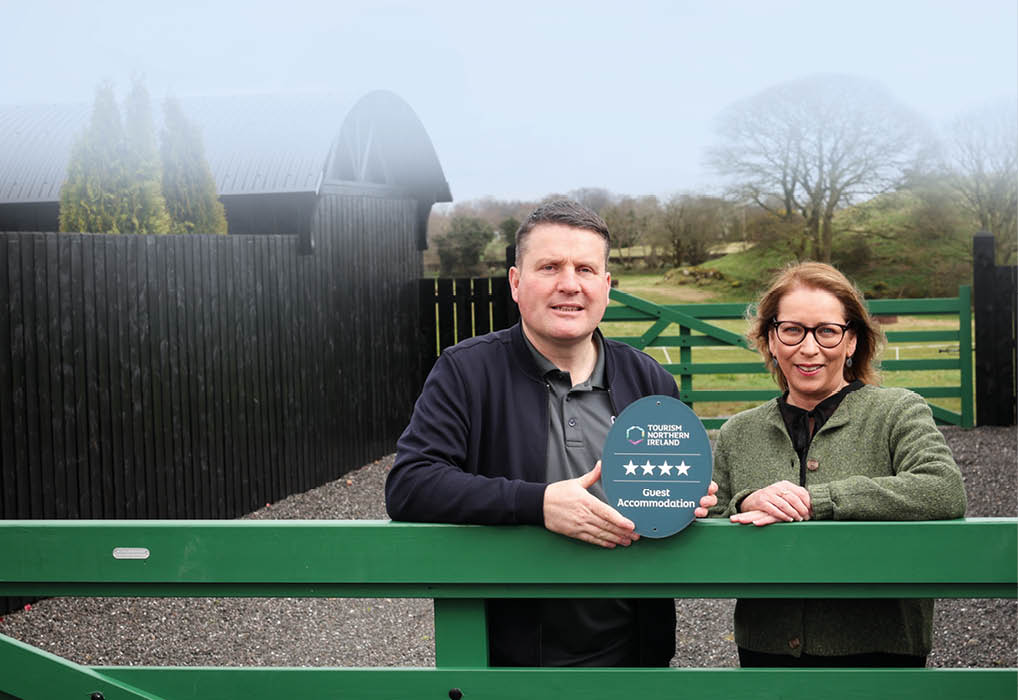 A man and woman standing in front of a fence. Description generated by AI