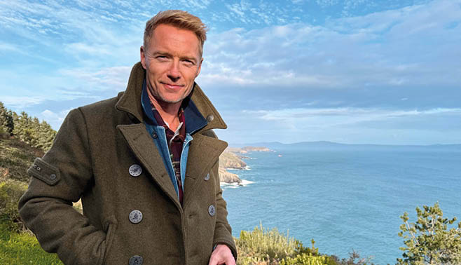A man wearing a coat and sunglasses. Description generated by AI