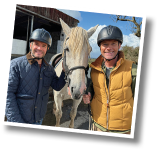 Two men standing next to a horse. Description generated by AI