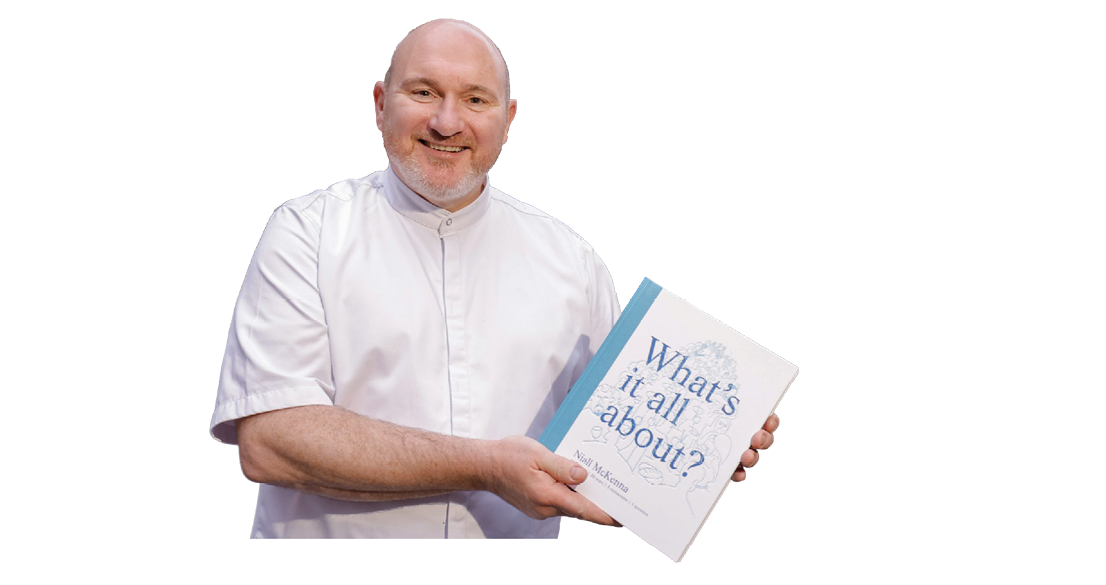 A person wearing a white shirt is smiling and holding a book titled “What's it all about?" Description generated by AI