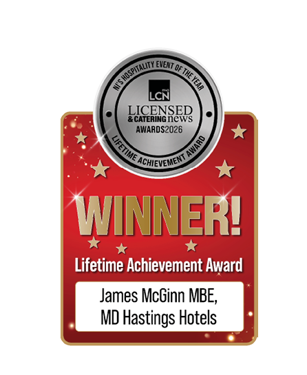 A red and gold award graphic with a silver seal at the top reads Winner Lifetime Achievement Award presented to James McGinn MBE, MD Hastings Hotels. Description generated by AI