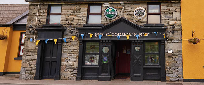 A stone building facade with a partially visible sign reading “O'Conno" and colorful triangular flags hanging below. Description generated by AI