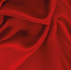 Smooth red fabric with soft folds and gentle shadows creating a flowing texture. Description generated by AI
