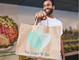 A person is holding a beige tote bag with two overlapping pastel-colored heart shapes on it. Description generated by AI
