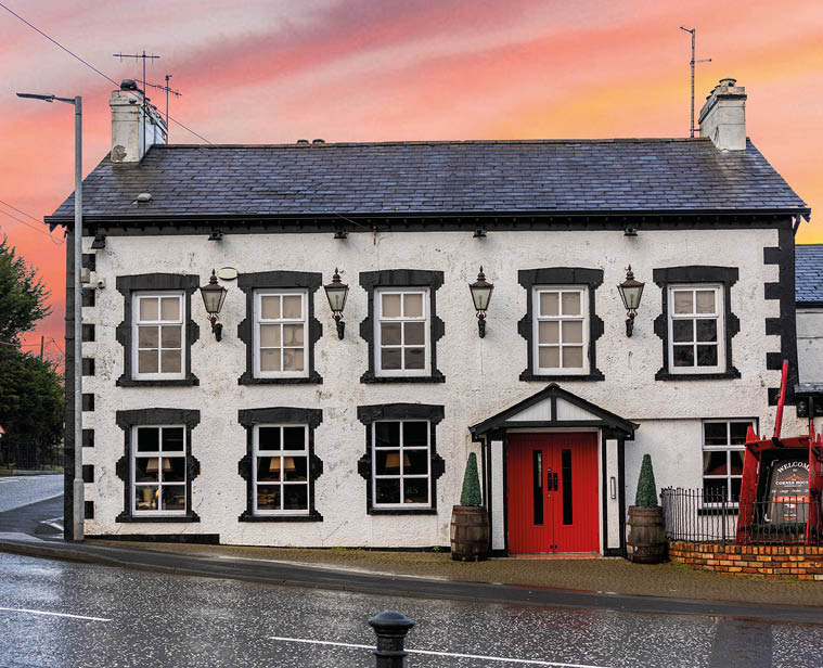 A two-story white building with black window frames and a bright red door stands beside a curved road under a colorful sunset sky. Description generated by AI