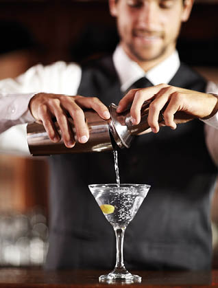 Shaken not stirred. Shot of a handsome young bartender mixing a cocktail.