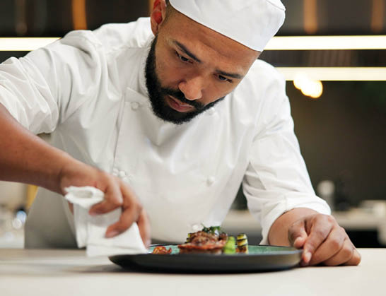 Man, chef and serious with plate in kitchen at restaurant for fine dining, meal and creativity. Male employee, professional and cooker with food for culinary, hospitality and catering service